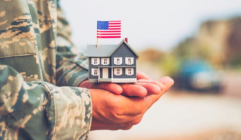 Veteran holding a small model home showing a Mortgage rate based on a VA Loan