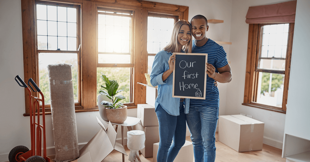 First-Time HomeBuyer Couple Smiling in the living room of their new home